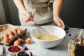 Close-up of woman preparing mixing pancake batter with a whisk in a bowl