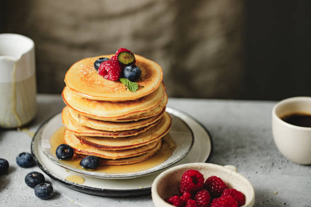 istock Freshly prepared pancakes served with berries and maple syrup on breakfast table 1938207061