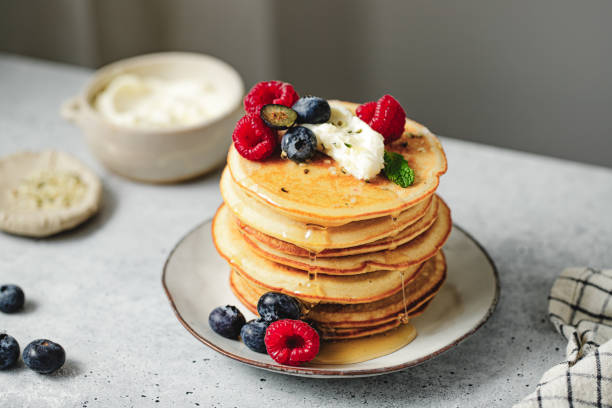 istock Stack of pancakes served with berries and maple syrup on breakfast table 1938207070