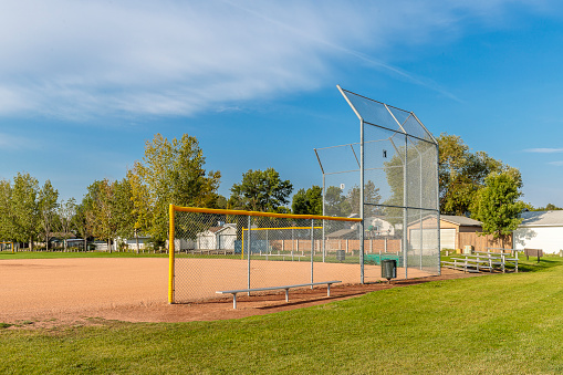 A low view of a yellow softball sitting on a painted white Foul Line on dirt of a softball field infield diamond. Sometimes this can be referred to as a Fair Line as it is in Fair Territory and the area from the edge of the line is Foul Territory.
