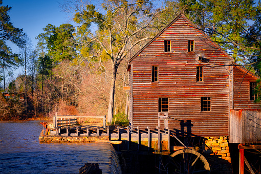 A nice sunny landscape of the gristmill and waterwheel by the dam at Yates Mill Park in Raleigh, NC.