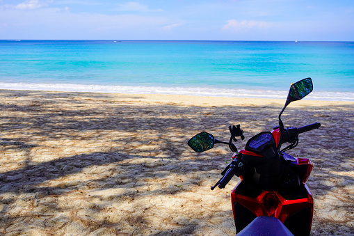 motorbike on the beach in Thailand. Blue sea and yellow sand. There is space for text for your advertisement