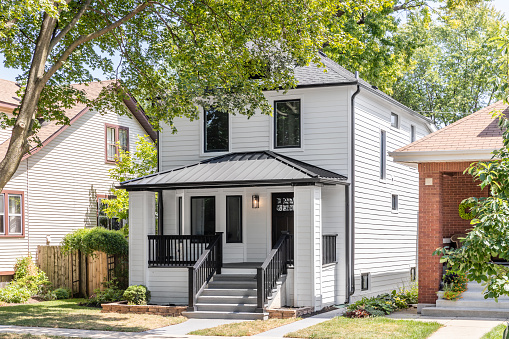 Chicago, IL, USA - August 24, 2021: A beautifully renovated home with white siding and black accents and a covered front porch.