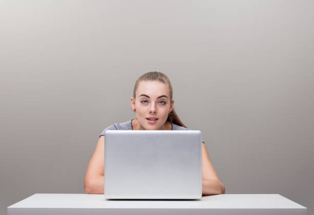 Full length of aged 20-29 years old who is beautiful with blond hair caucasian female business person standing in front of white background wearing businesswear and high heels who is furious who is working and using computer
