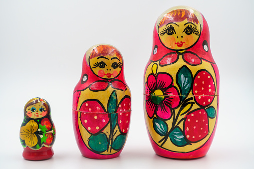 Russian matryoshka nesting dolls, hand-painted with folk motifs, red floral decoration, cultural handicraft, ornamental pieces, symbol of Russian heritage, wooden toys. White background