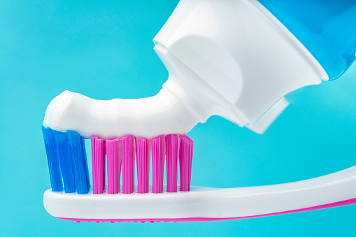 Close up of toothpaste tube putting paste on toothbrush. Oral health and dental hygiene to avoid diseases.