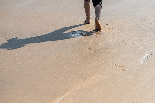 A child's feet walking on the beach