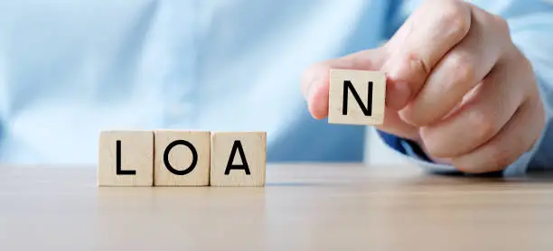 Photo of Hand holding wood blocks with loan word, Business concept