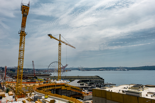 Tall cranes and Seattle waterfont with ferris wheel surround construction