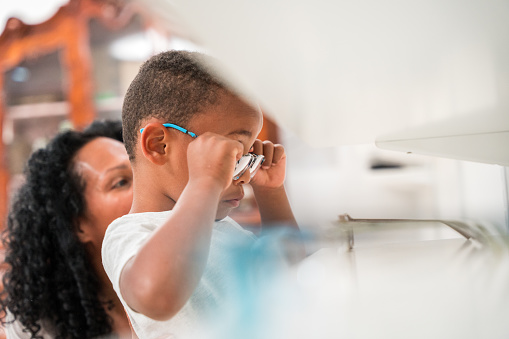 Engagement in pediatric eye care with a young Black boy examining spectacles for health and vision, child patient interaction in focus.