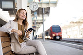 A businesswoman seated on a bench at the train station