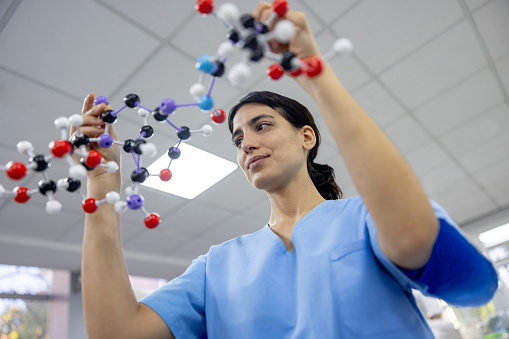 Latin American female scientist holding a molecule model at the laboratory