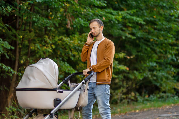 istock Man talking on mobile phone and pushing stroller outdoors. Father on paternity leave. 1938557297