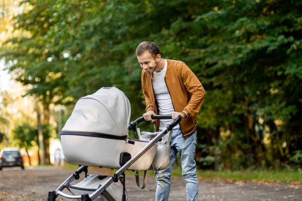 istock happy father looking and pushing infant baby stroller while walking in the park smiling and talking to his infant 1938557537
