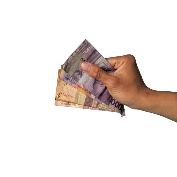 istock Man's hand holding rupiah money isolated on white background. 1938558859