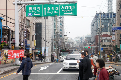 Seoul, South Korea - November 27, 2016.\nBusy road in downtown Seoul, South Korea with people crossing the road at a pedestrian crossing.