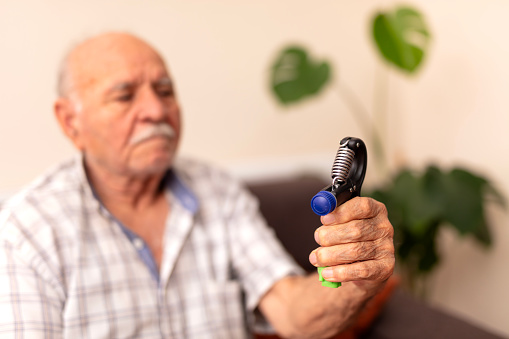 Close-up of a senior man holding a hand grip at home