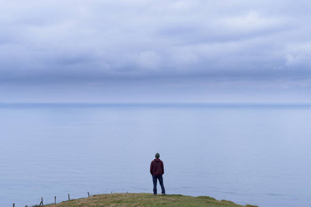 lonely man with overcast sky at water's edge