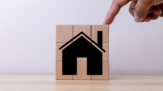 Real Estate Market Growth Concept. businessman or a home or real estate broker. taxes and profits. Wooden cube block puzzle with pictures at home
