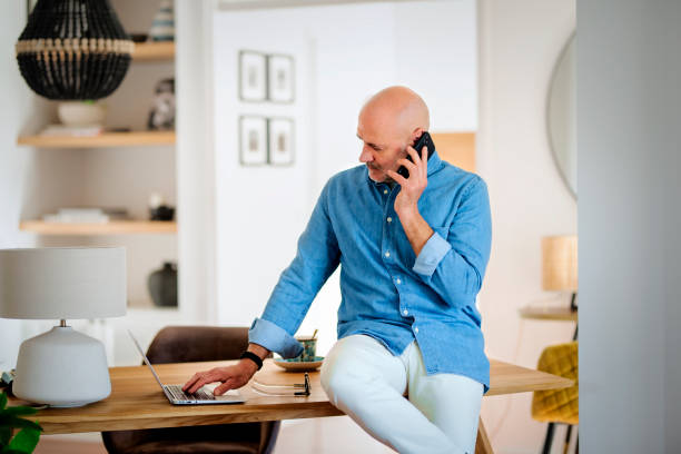 istock Mid aged man wearing casual clothes and using smartphone while working from home 1938690084