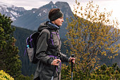 Lifestyle photography of people and nordic walking, tourism concept. Female portrait of woman, who traveling in mountains. Person doing hiking with warm sportswear outdoors. Girl is backpacker with rucksack for touristic equipment.
