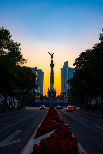 The Angel of Independence statue placed on Reform avenue in Mexico city against colorful orange sunset sky