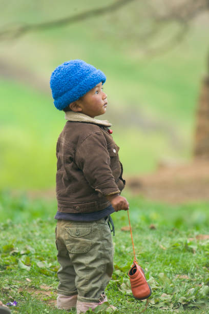 happy little boy sitting in the rain with a toy without an umbrella