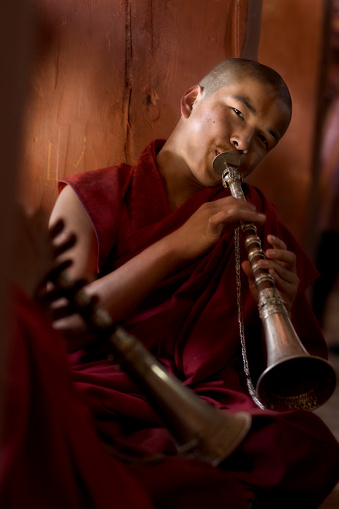 Punakha Valley, Bhutan - April 15, 2008: Monk blows a decorated horn instrument inside the fortress monastery of Punakha Dzong