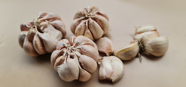Garlic are isolated in beige background, usually used as a cooking spice and also as herbal medicine.