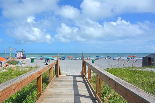 View of beach from wooden boardwalk over the dunes near downtown Cocoa Beach on the Atlantic coast of Florida