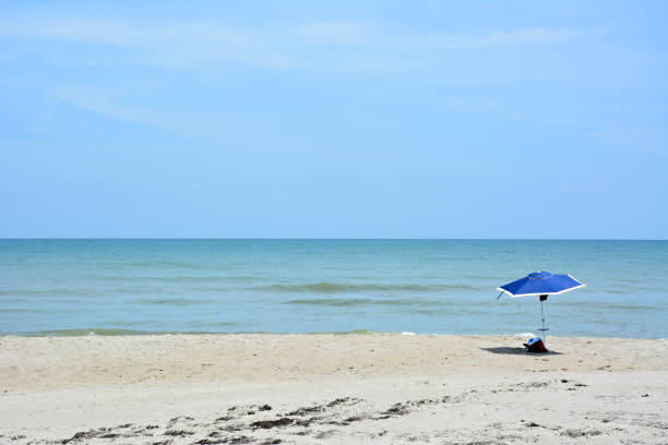 Empty sandy beach under blue skies with a single umbrella or parasol in Cocoa Beach, Florida