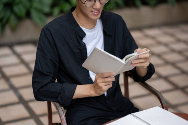 istock A happy Asian man is reading a book or checking his schedule in his planner book at a table outdoors 1938800669