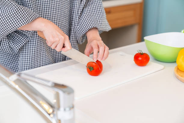 istock woman cooks in a kitchen,cut the tomato,hands, 1938843515