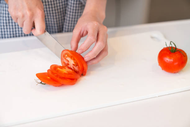 woman cooks in a kitchen,cut the tomato,hands,