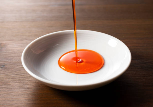 istock Pour chili oil sauce into a ceramic dish. Wooden background. Table. 1938857779