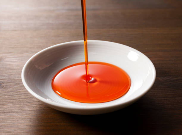 istock Pour chili oil sauce into a ceramic dish. Wooden background. Table. 1938857782