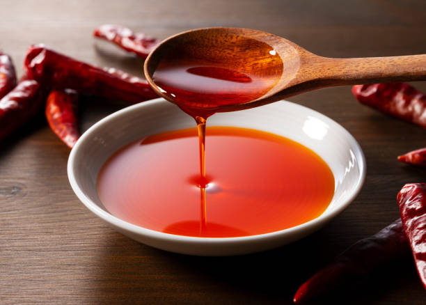 istock Pour chili oil with a spoon into a ceramic dish placed on a wooden background. 1938857794