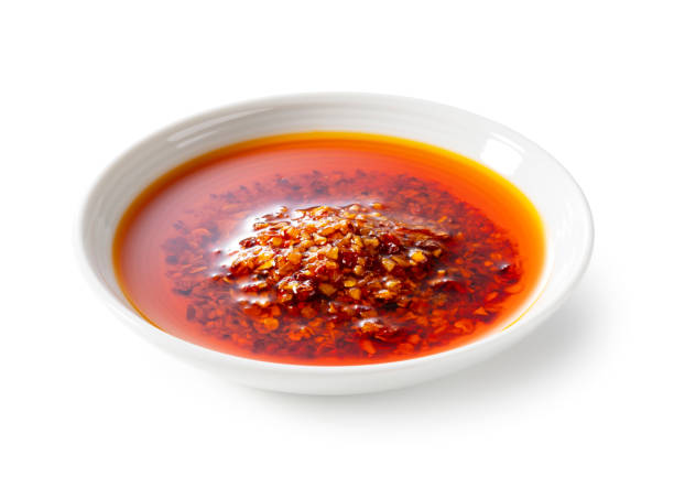 istock Edible chili oil in a ceramic dish set against a white background. 1938857813
