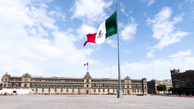 slow motion shot of mexican flag flying on the zocalo in front of national palace in mexico city