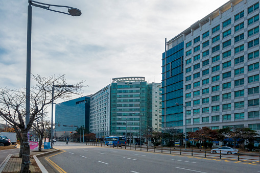 Incheon, S. Korea - Nov 27, 2019: Wide roads and modern buildings as a major thoroughfare. Quiet scene with little vehicle and pedestrian traffic in the foreground.