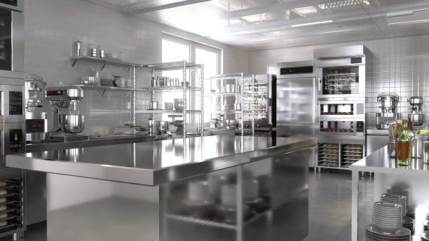 istock Empty clean stainless steel island table in commercial, professional bakery kitchen with convection, deck oven, freezer, refrigerator, shelf, cabinet, equipment in background 1938952590