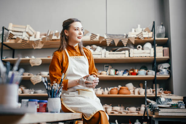 istock Woman potter with clay sitting on table in the workshop 1938972746