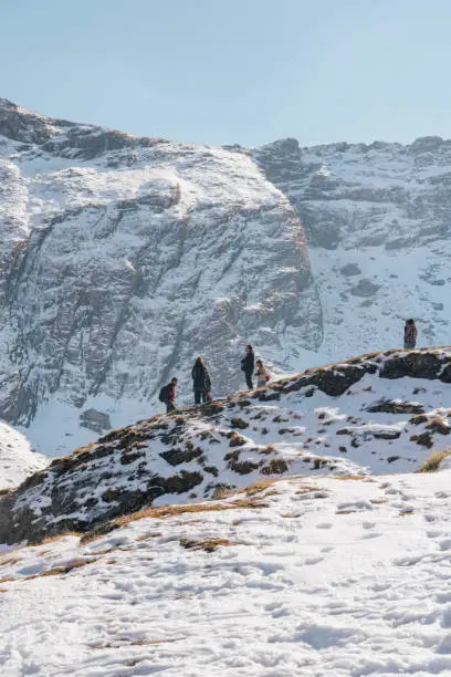 Hikers walking on the top of a snowy cliff in the Fagaras mountain range in Romania.