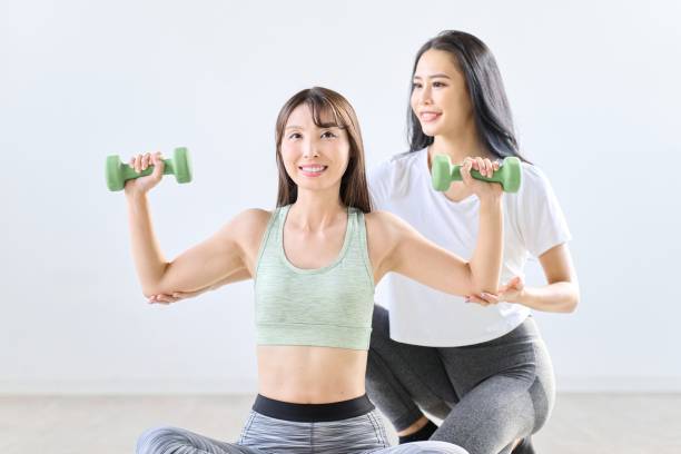 istock A woman being taught dumbbell training by a trainer 1939073828