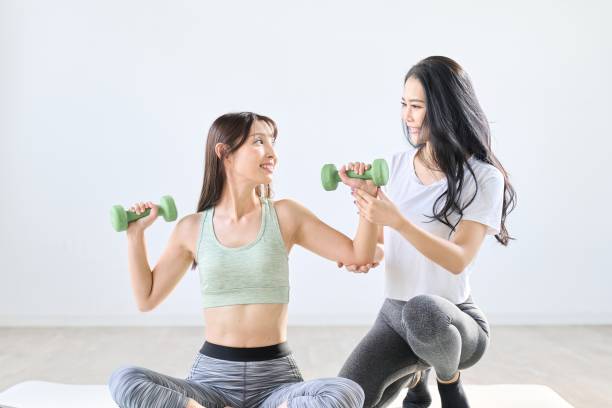 istock A woman being taught dumbbell training by a trainer 1939074333