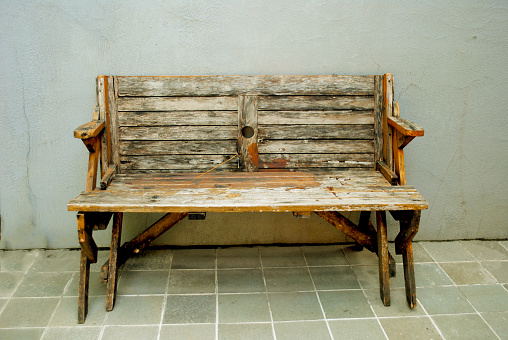 Weathered wooden bench surrounded by yellow blooming Wild Mustard and other weeds.