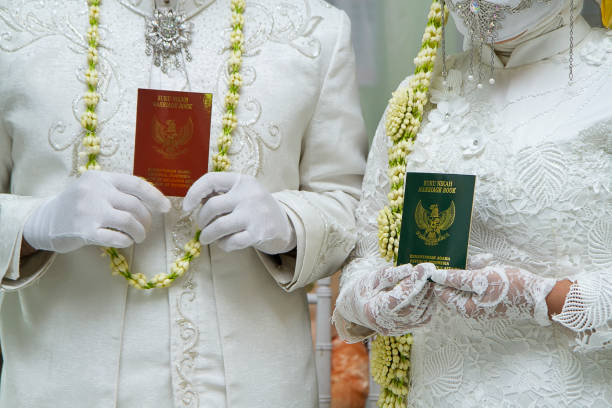 bride and groom holding indonesian marriage certificate - proof of love стоковые фото и изображения