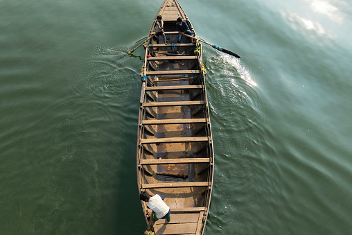 Massanjore, Jharkhand, India - December 26th 2023: Top view of a wooden boat rowing on green water by a group of children in India