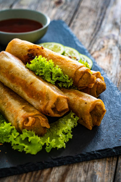 istock Spring rolls filled with meat and vegetables served with soy sauce on wooden table 1939122176
