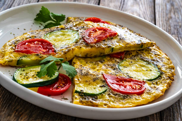 istock Omelet - scrambled eggs with cheese, zucchini and tomatoes on wooden table 1939125259